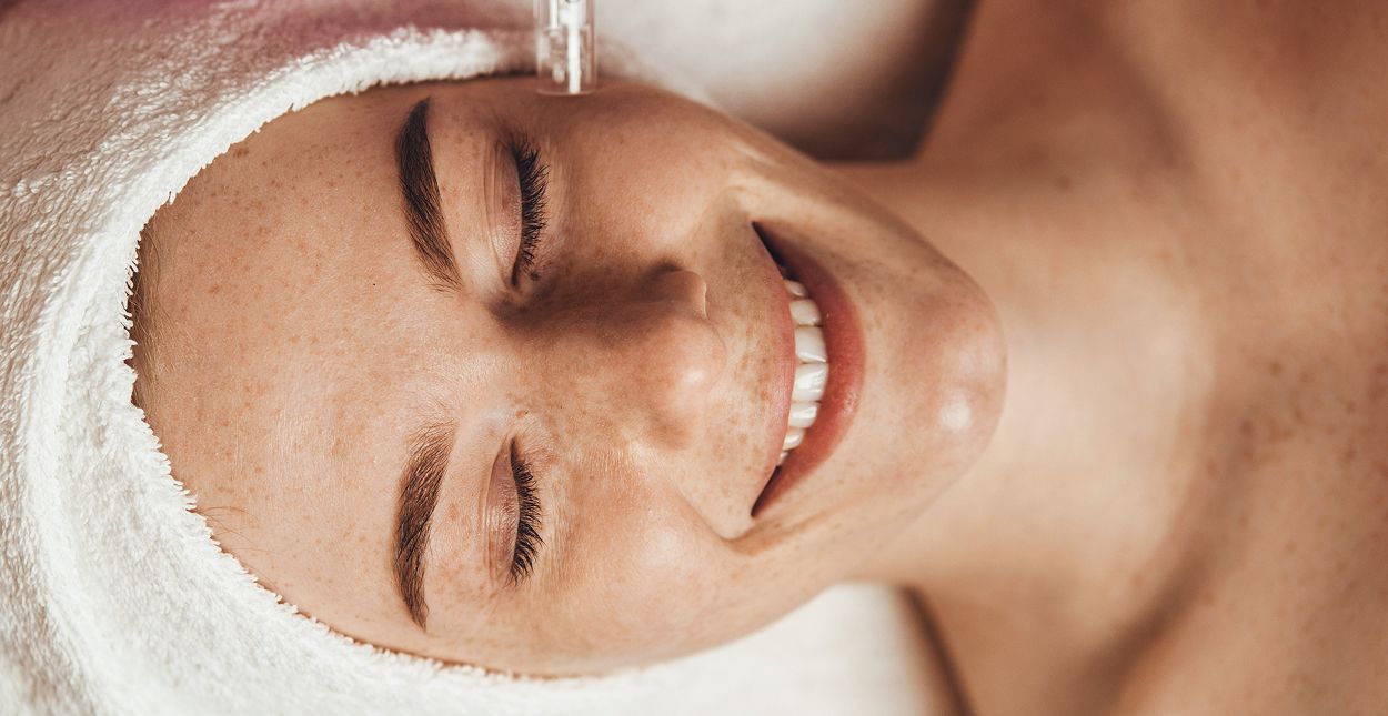 Woman smiling during a facial treatment session.