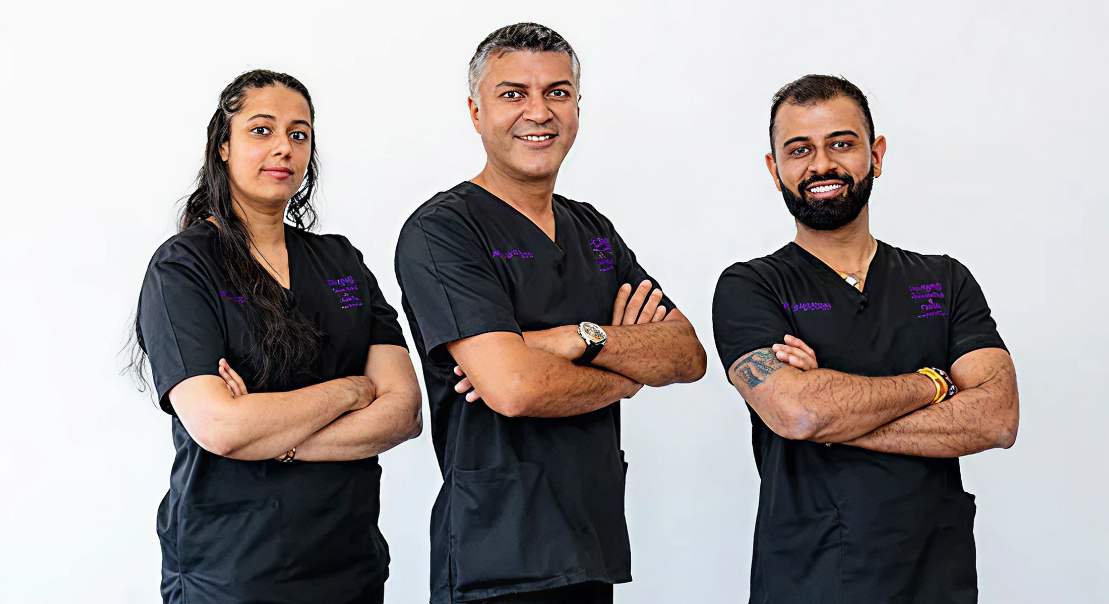 Medical team in black scrubs posing together.