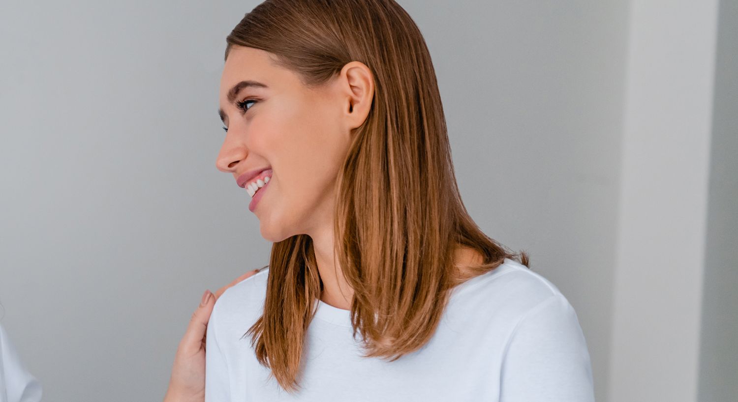 Smiling woman in casual white shirt, profile view.