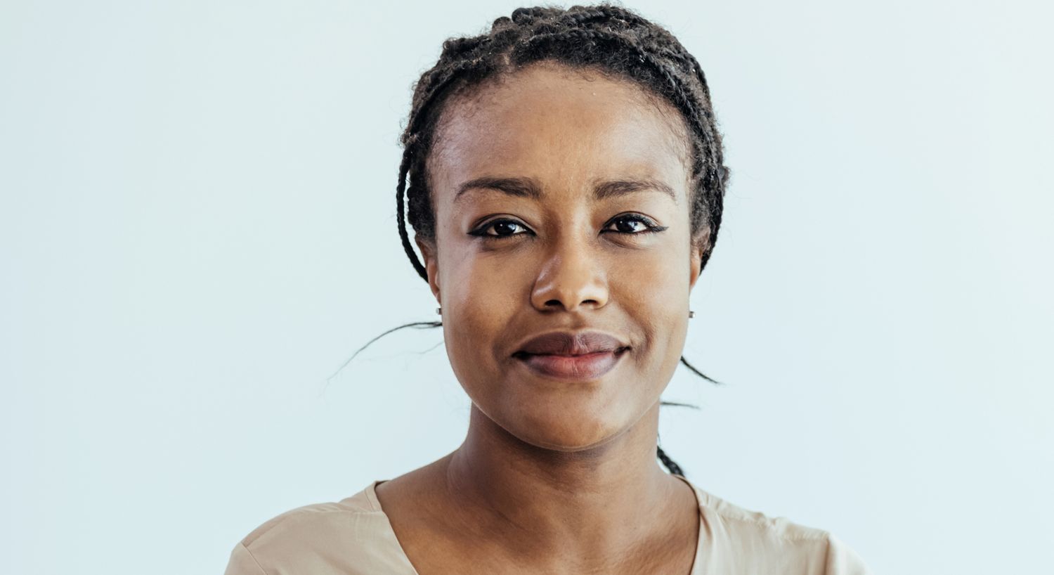 Smiling woman with braided hair against light background.