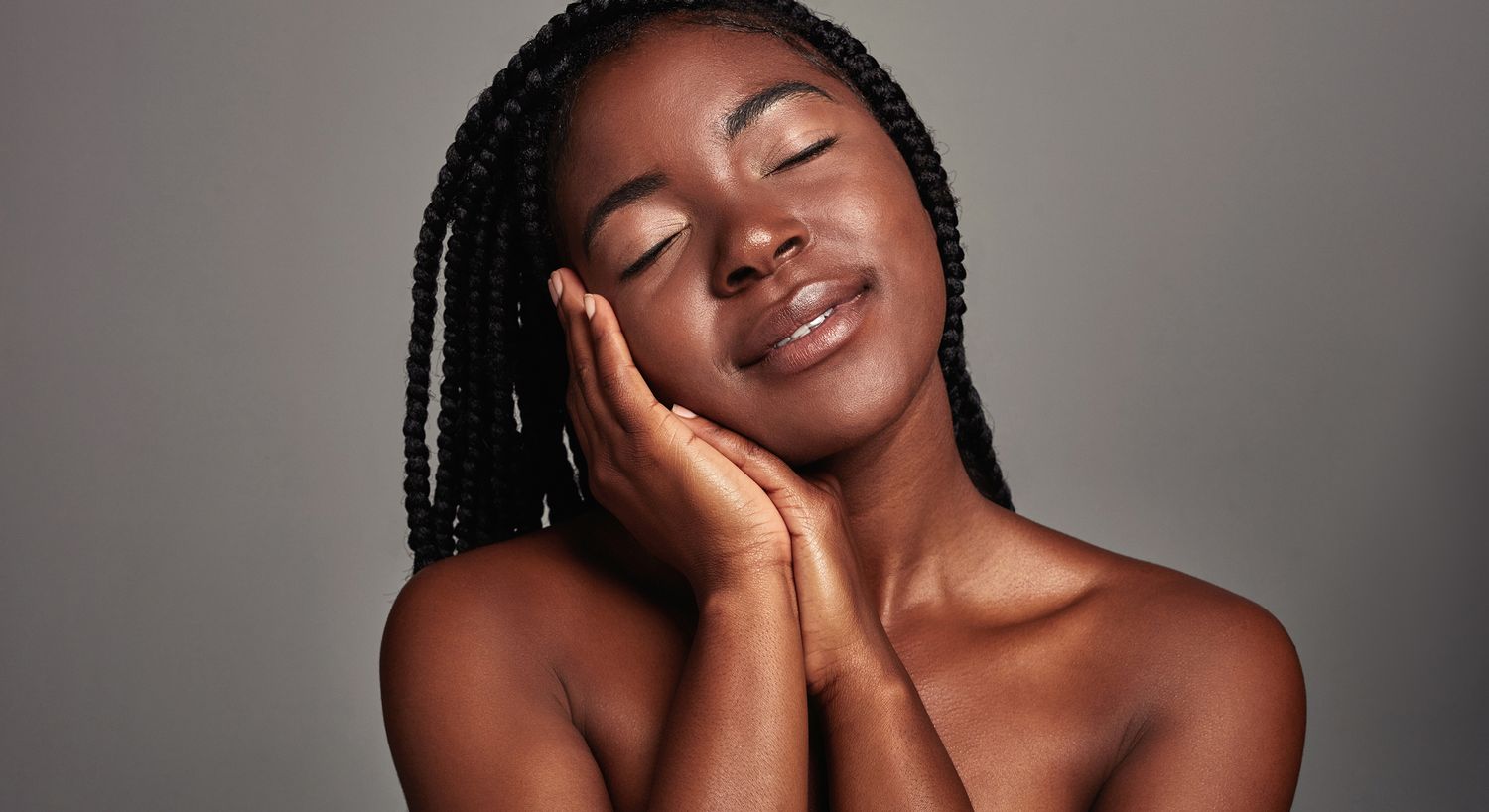 Smiling woman with braided hair and closed eyes.