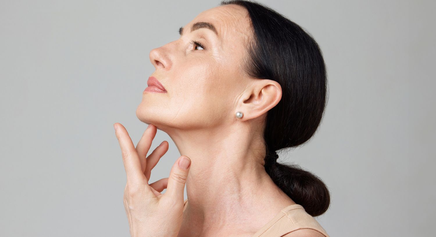 Woman gently touching her jawline, profile view.