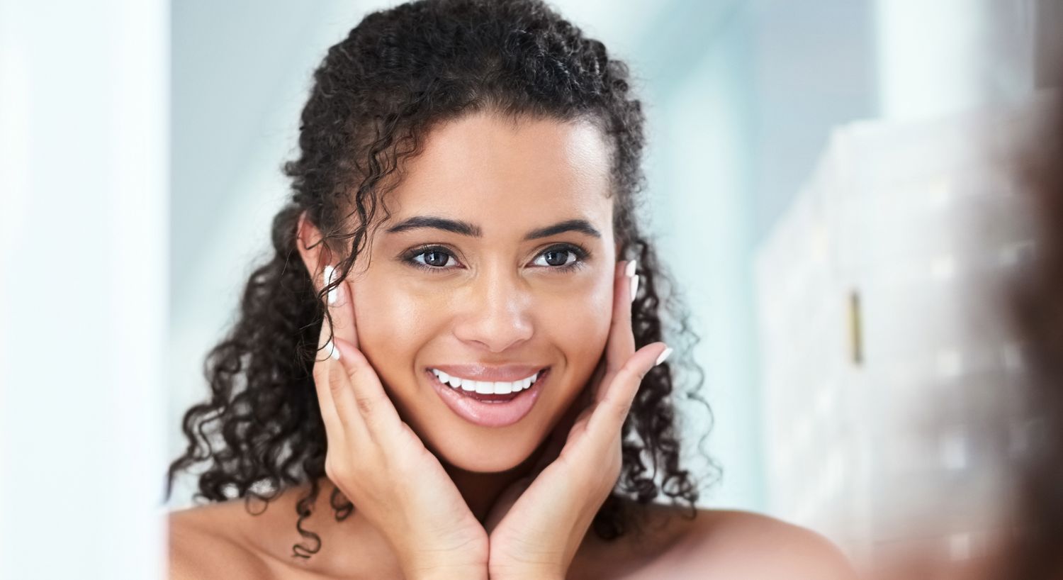 Smiling woman touching her face in mirror.