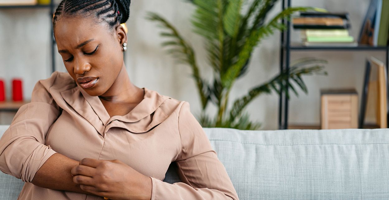 Woman experiencing discomfort while seated indoors.