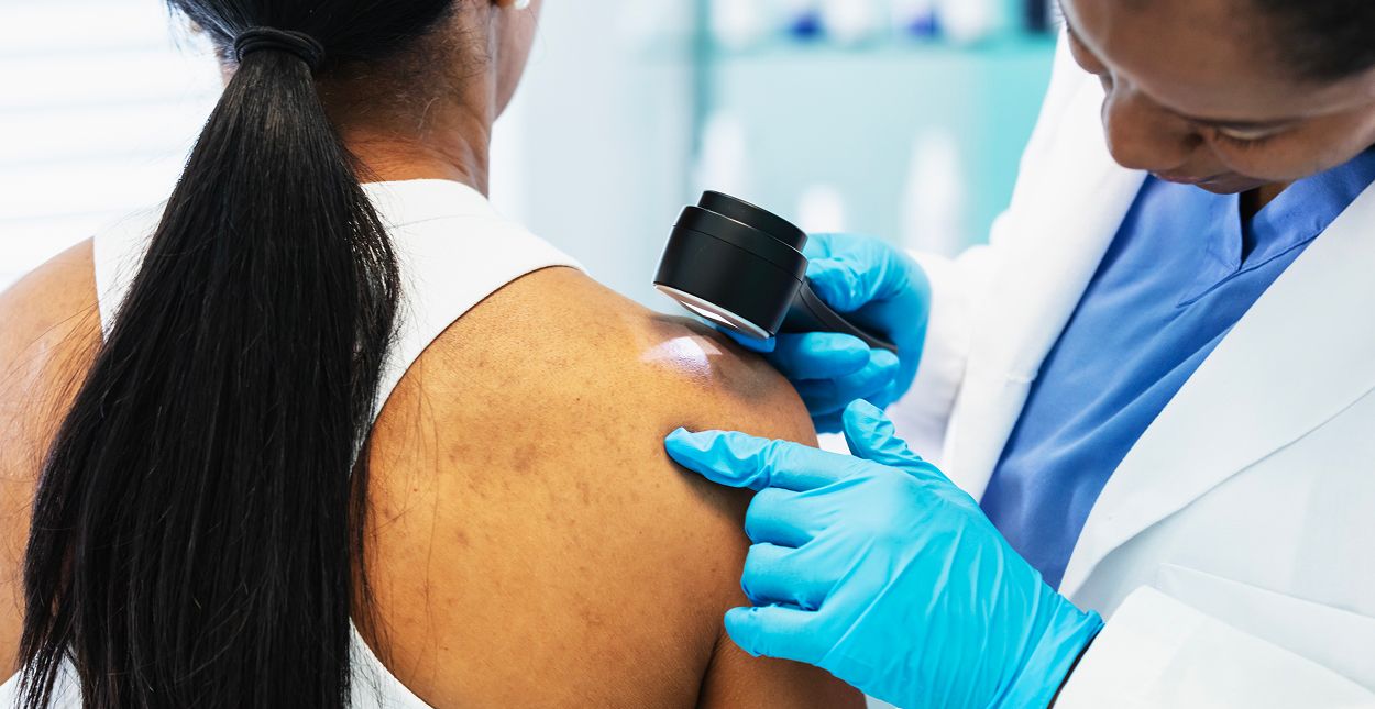 Doctor examining a patient's skin with a device.